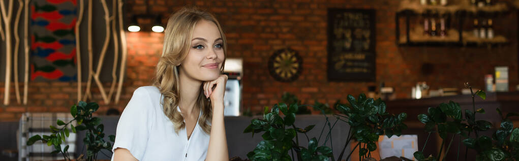 młoda blondynka patrzy i uśmiecha się w kawiarni, sztandar - Zdjęcie, obraz