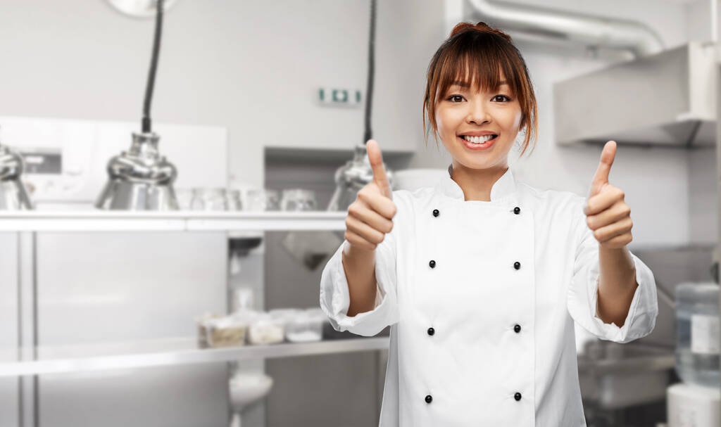 uśmiechnięta kucharka pokazująca kciuki w kuchni - Zdjęcie, obraz