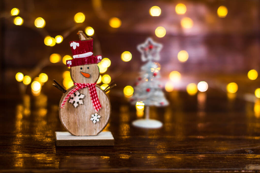 Detailní záběr malého dřevěného sněhuláka a vánoční strom proti bokeh světla na pozadí - Fotografie, Obrázek