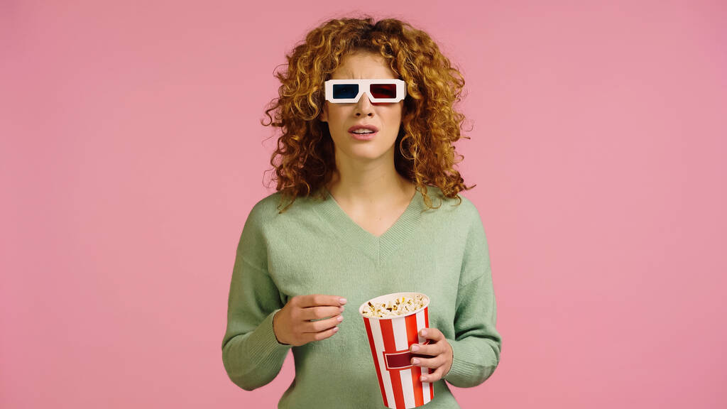 ustaraná žena v 3D brýle drží popcorn vědro při sledování filmu izolované na růžové - Fotografie, Obrázek