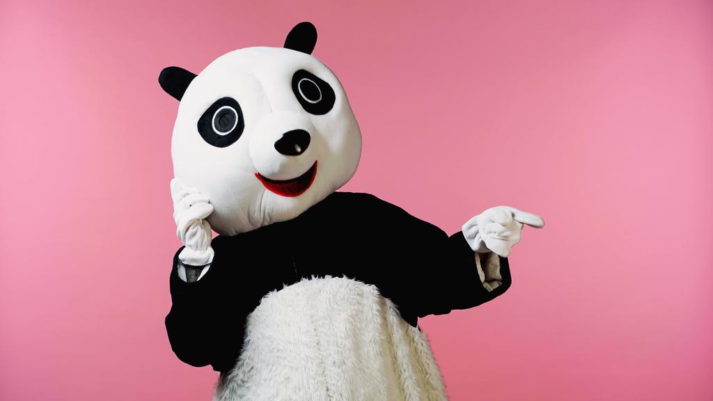 osoba ve šťastné panda medvěd kostým ukazuje prstem izolované na růžové  - Fotografie, Obrázek