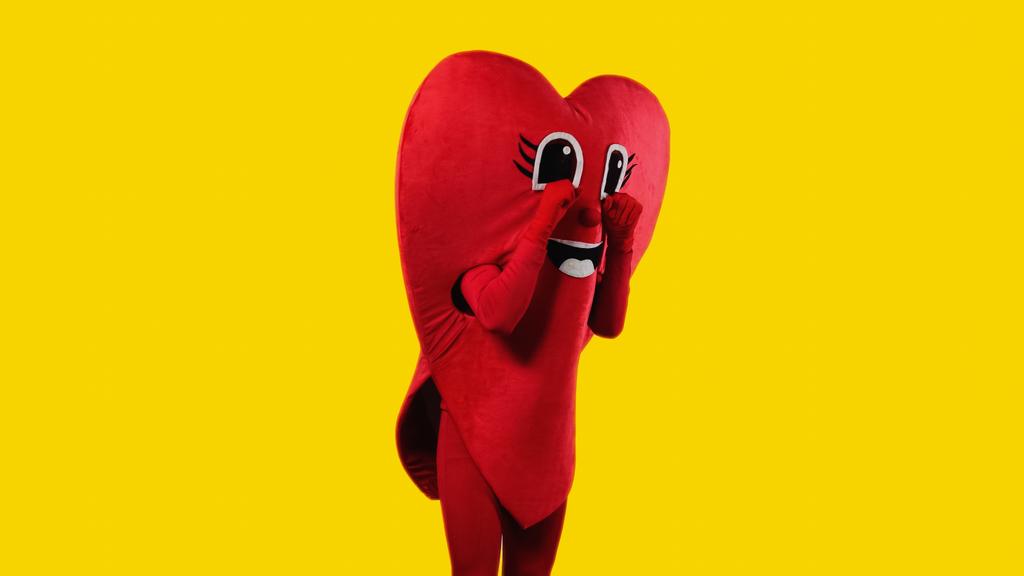 person in heart costume touching cartoon eyes while imitating crying isolated on yellow - Foto, Bild