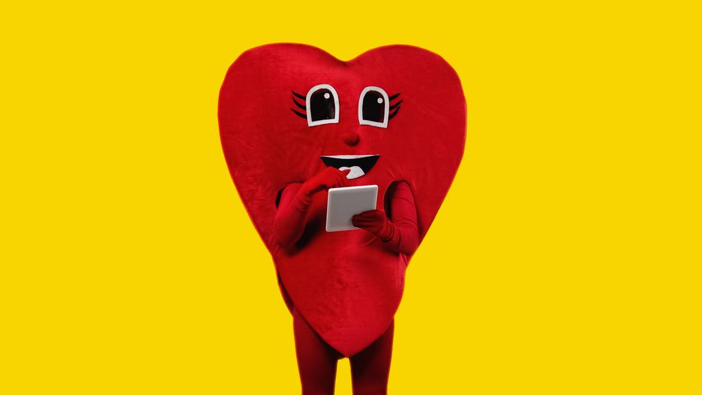 osoba v červeném kostýmu drží digitální tablet izolované na žluté - Fotografie, Obrázek