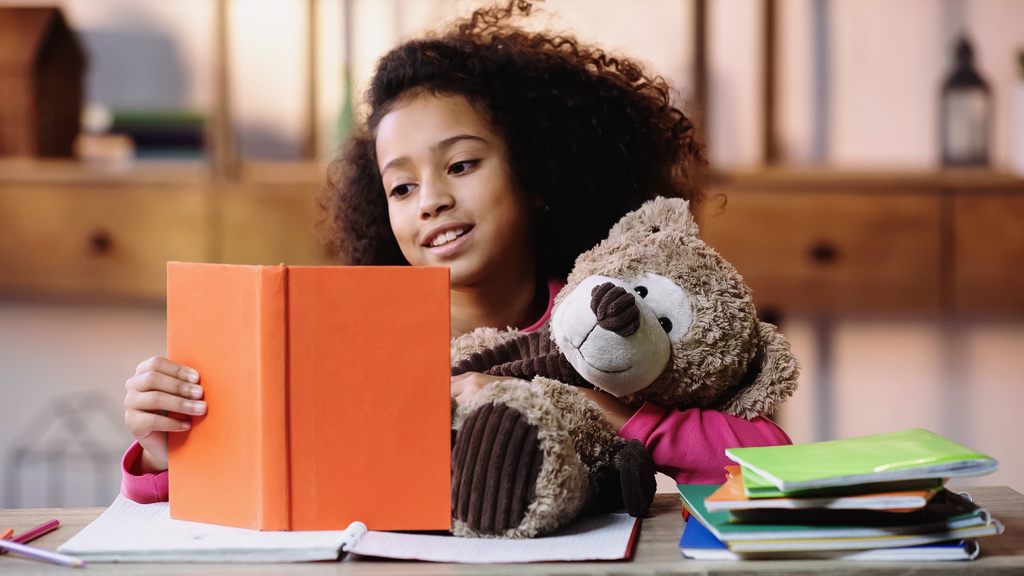 Mutlu Afro-Amerikan çocuk oyuncak ayıya kitap okuyor.  - Fotoğraf, Görsel
