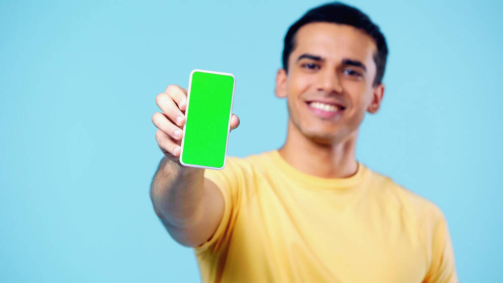 homem feliz desfocado segurando smartphone com tela verde isolada no azul - Foto, Imagem
