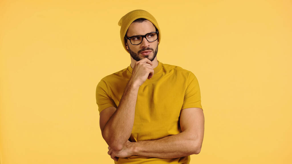jovem pensativo em chapéu gorro isolado em amarelo  - Foto, Imagem