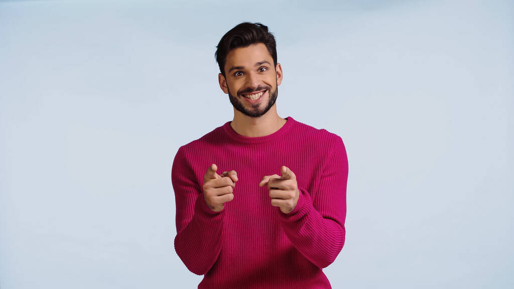 ピンク色のセーターを着た幸せな男は笑顔で指差し込みながら  - 写真・画像