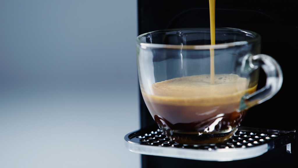 закрыть кофеварку, наливая напиток в чашку на сером  - Фото, изображение