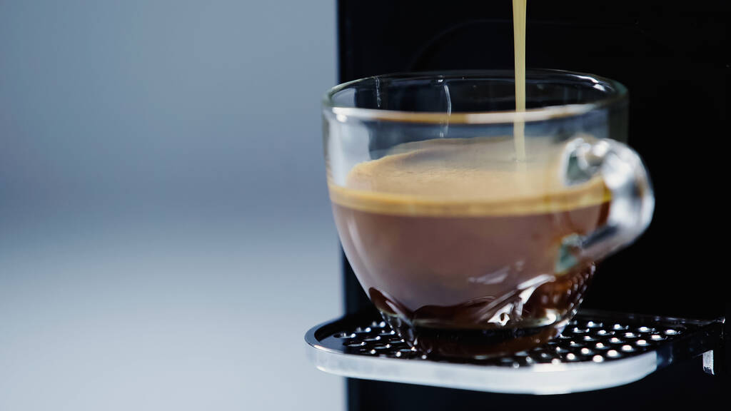 close-up van automatische koffiezetapparaat gieten americano in kopje op grijs  - Foto, afbeelding
