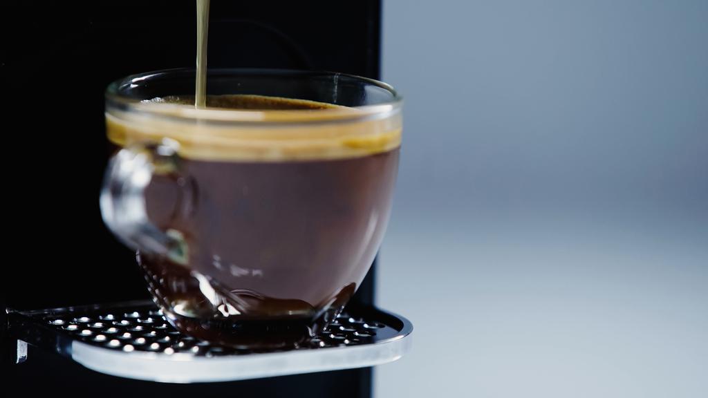 закрытие автоматической кофеварки наливая напиток в чашку на серый  - Фото, изображение