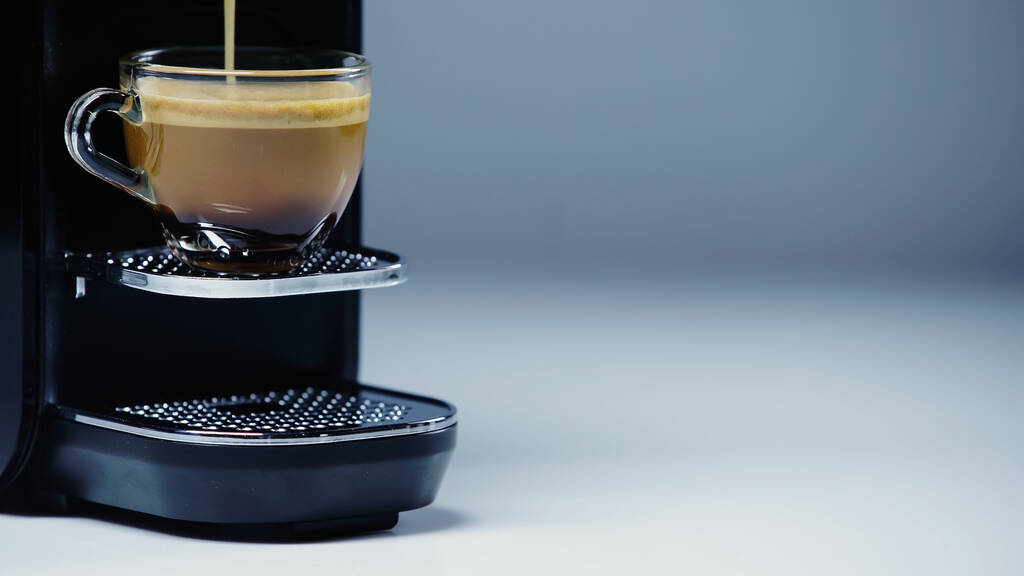 automatický kávovar nalévání horký nápoj do skleněného kelímku na šedé - Fotografie, Obrázek