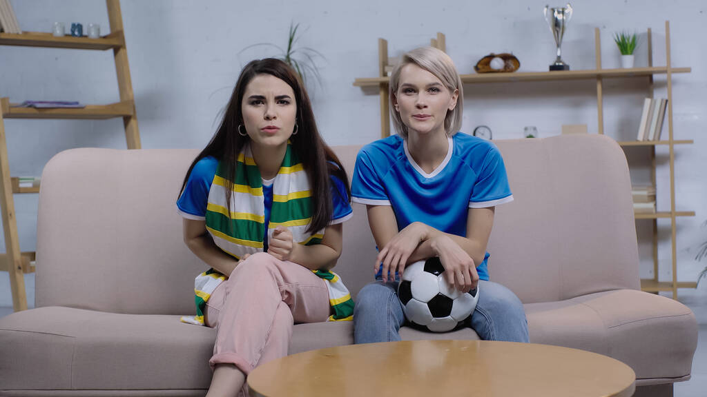 concentrados aficionados al fútbol viendo el campeonato en la televisión mientras están sentados en el sofá en casa - Foto, imagen