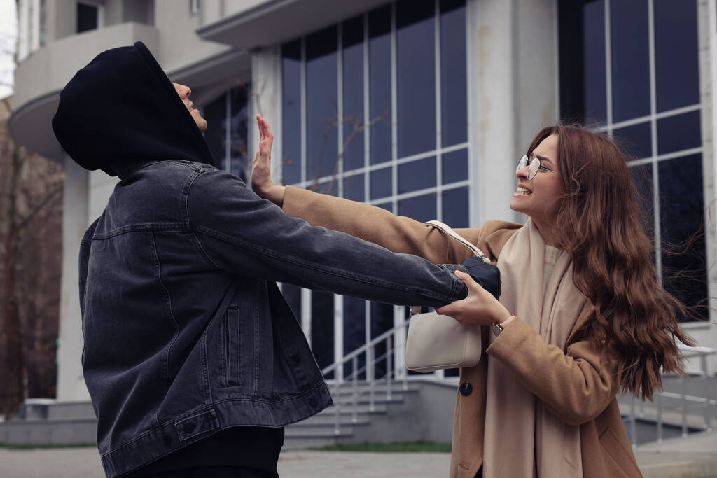 Une femme se battant avec un voleur alors qu'il essayait de voler son sac dans la rue de la ville. Concept d'autodéfense - Photo, image