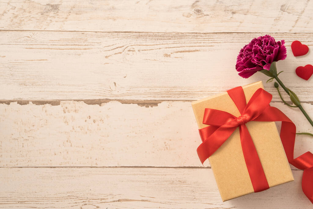 Kraft ajándék doboz piros szalaggal íj és szegfű, koncepció ajándékozás anyák napján meglepetés, lapos fektetés, felső nézet - Fotó, kép