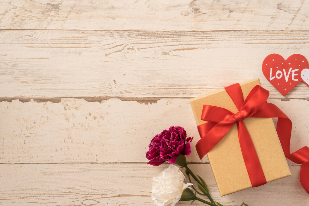 Caja de regalo Kraft con lazo de cinta roja y clavel, concepto de dar regalo en el día de la madre como sorpresa, laico plano, vista superior - Foto, imagen