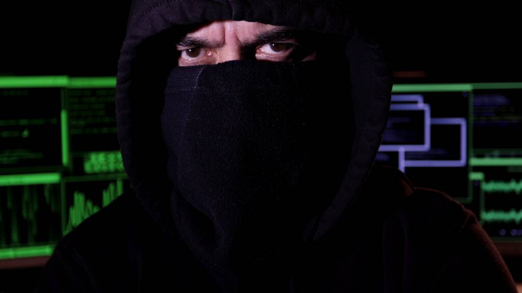 Close-up, hacker cibernético con capucha y la cara cubierta mira a la cámara con mirada seria. Concepto de ciberterrorismo. - Foto, imagen