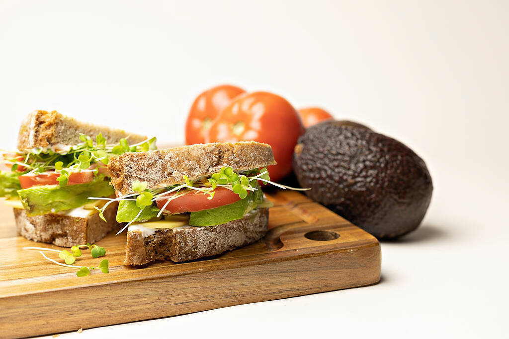 сэндвич с лососем, авокадо, огурцом и салатом на белом деревянном фоне - Фото, изображение