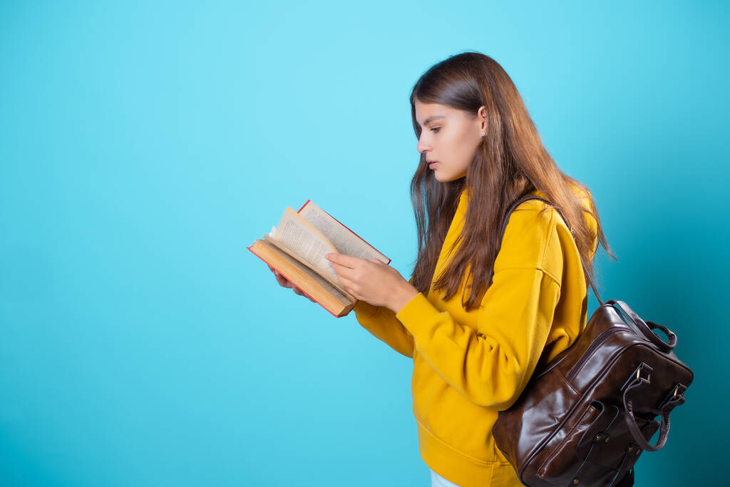 A student with a book in her hands, reading a textbook and preparing for a new lesson. - Photo, Image