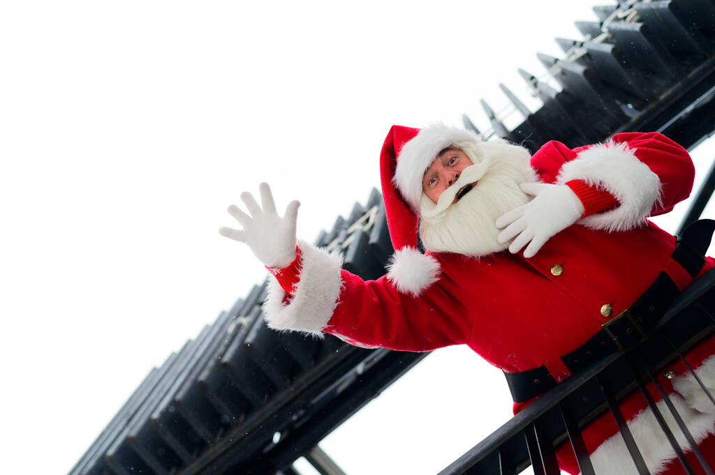Santa Claus mira desde las escaleras y desea una feliz Navidad al aire libre - Foto, imagen