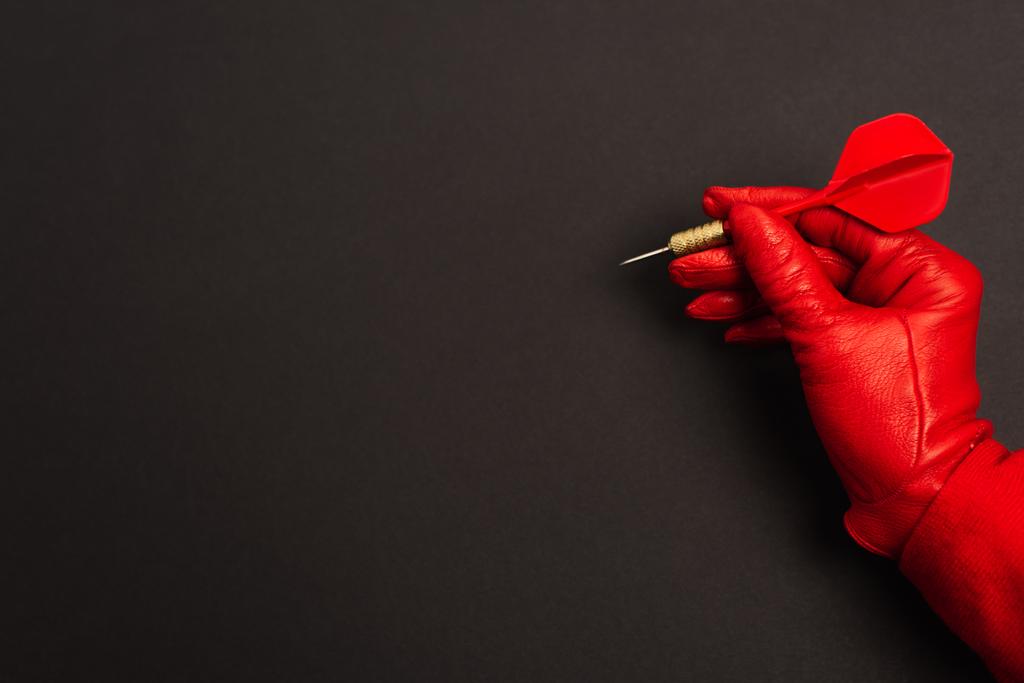 Kırpılmış görüntüde kırmızı eldivenli kadın elinde siyah dart okuyla  - Fotoğraf, Görsel