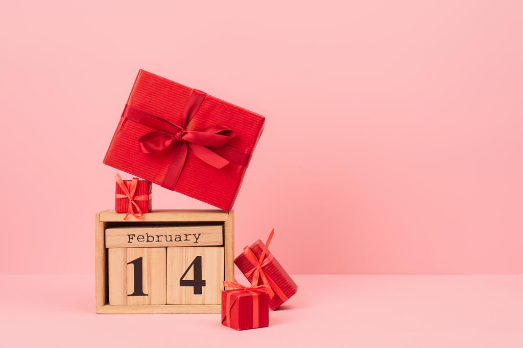 red gift boxes on wooden calendar with 14 february lettering on pink - Foto, Bild