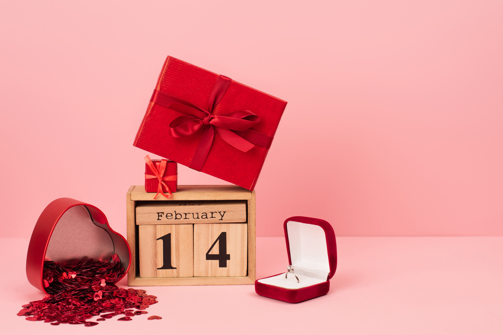 red gift boxes on calendar with 14 february near engagement ring and confetti on pink - Foto, immagini