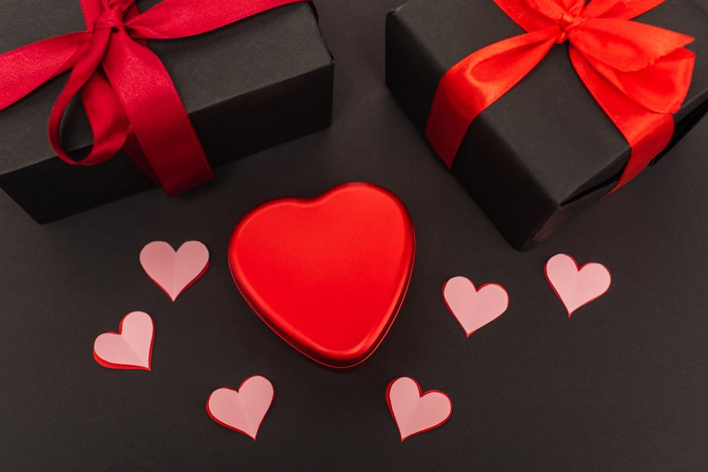top view of paper cut hearts and metallic box near wrapped presents on black - Photo, Image