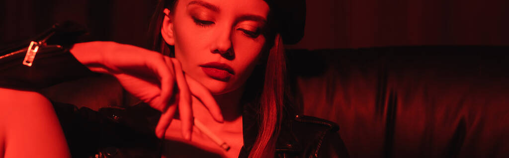 jeune femme sensuelle fumant à la lumière rouge sur fond noir, bannière - Photo, image