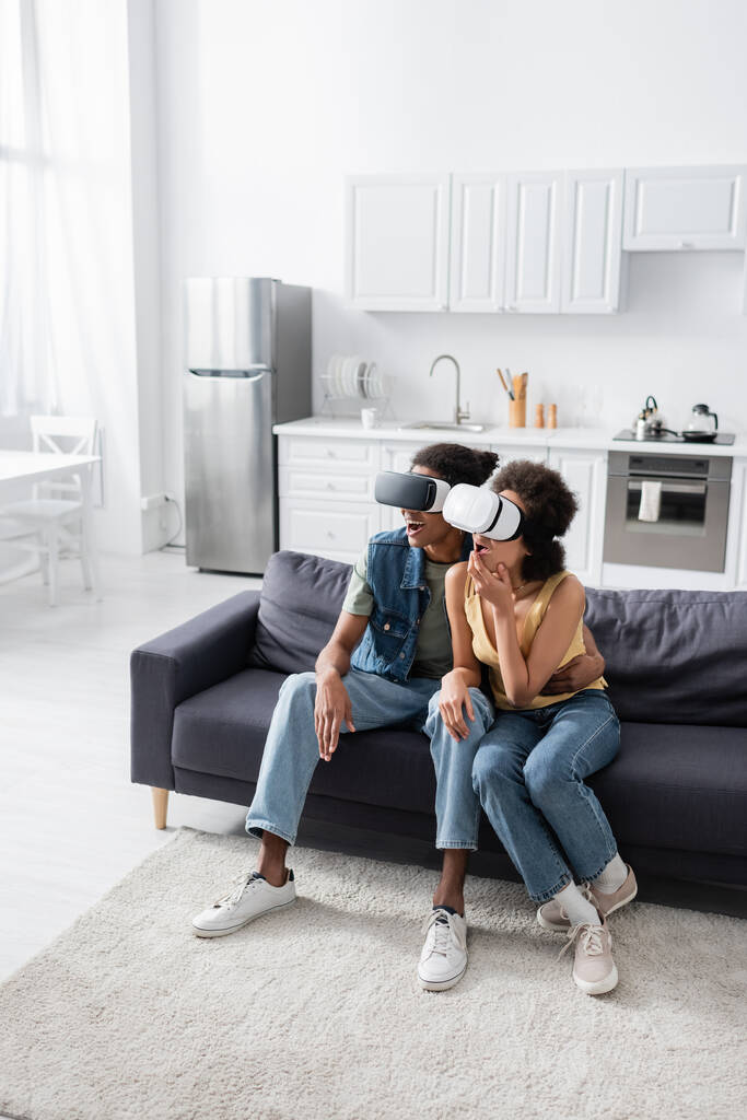 Izgalmas afro-amerikai pár vr headset ül a kanapén otthon  - Fotó, kép