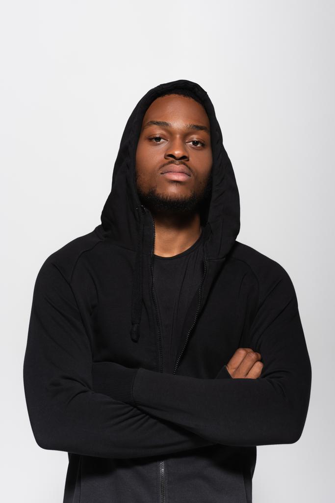 young african american man in hoodie standing with crossed arms isolated on grey - Foto, Bild