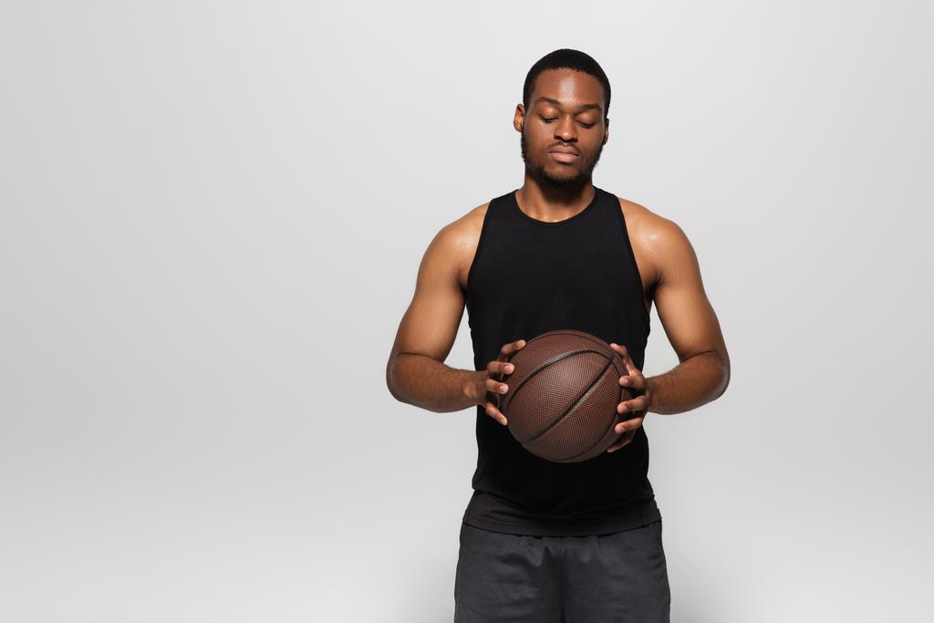 アフリカ系アメリカ人選手は灰色で隔絶されたバスケットボールを - 写真・画像