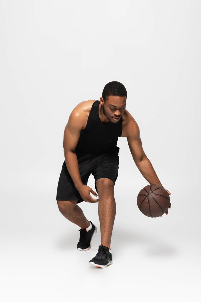 tutta la lunghezza dell'uomo afro-americano che gioca a basket su grigio - Foto, immagini