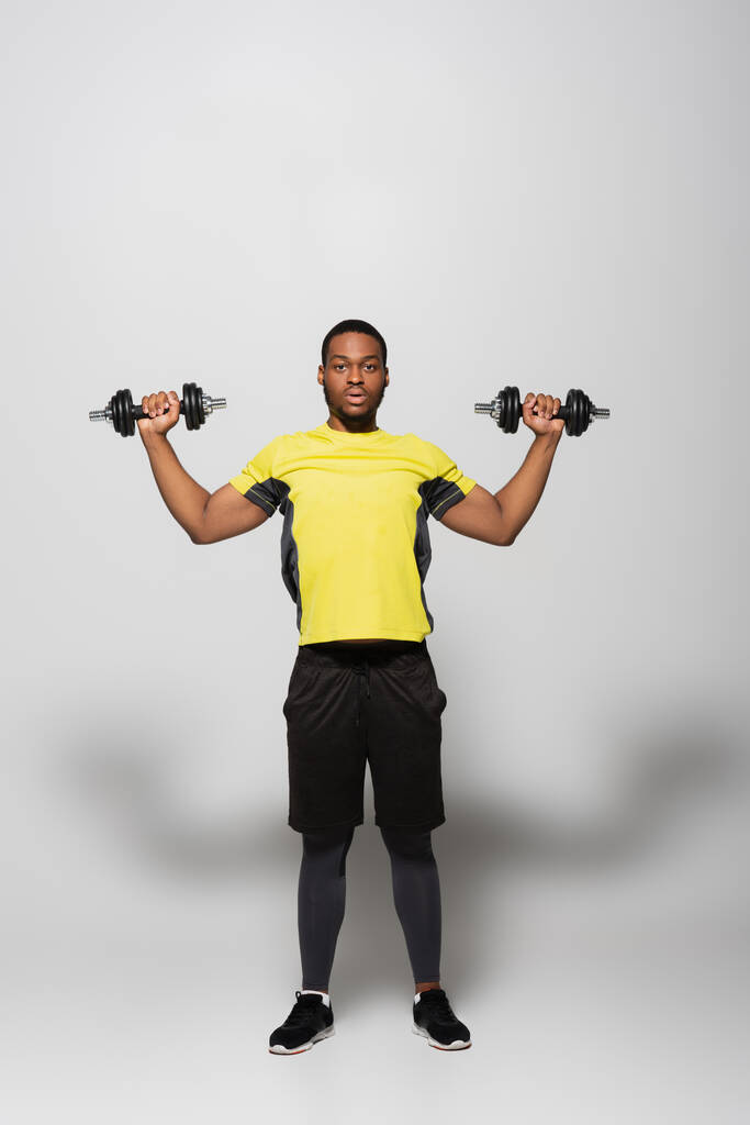 plná délka africký americký sportovec cvičit s těžkými činky na šedé  - Fotografie, Obrázek