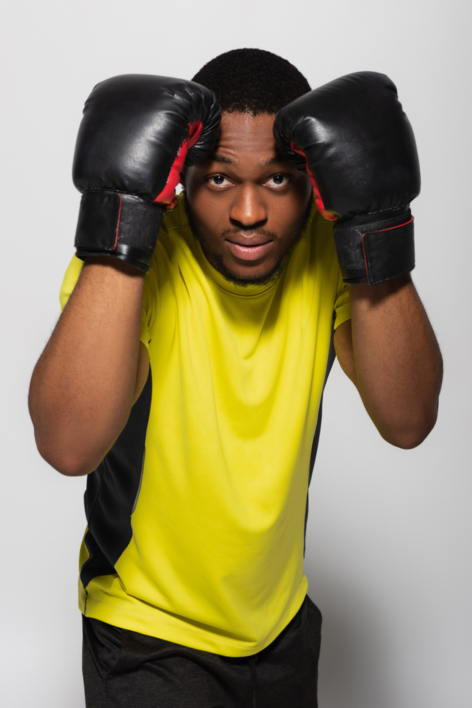 deportista afroamericano haciendo ejercicio con guantes de boxeo aislados en gris - Foto, imagen