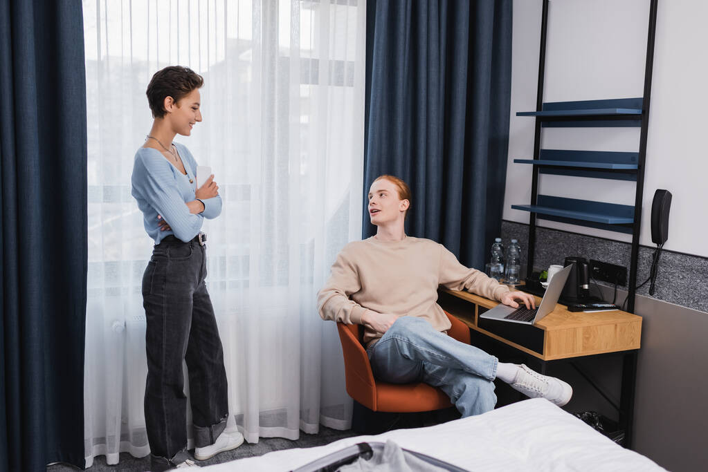 Positives Paar nutzt Geräte in modernem Hotelzimmer  - Foto, Bild