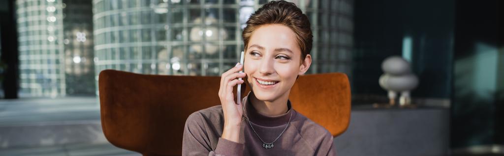Young woman talking on cellphone in hotel lobby, banner  - Фото, изображение
