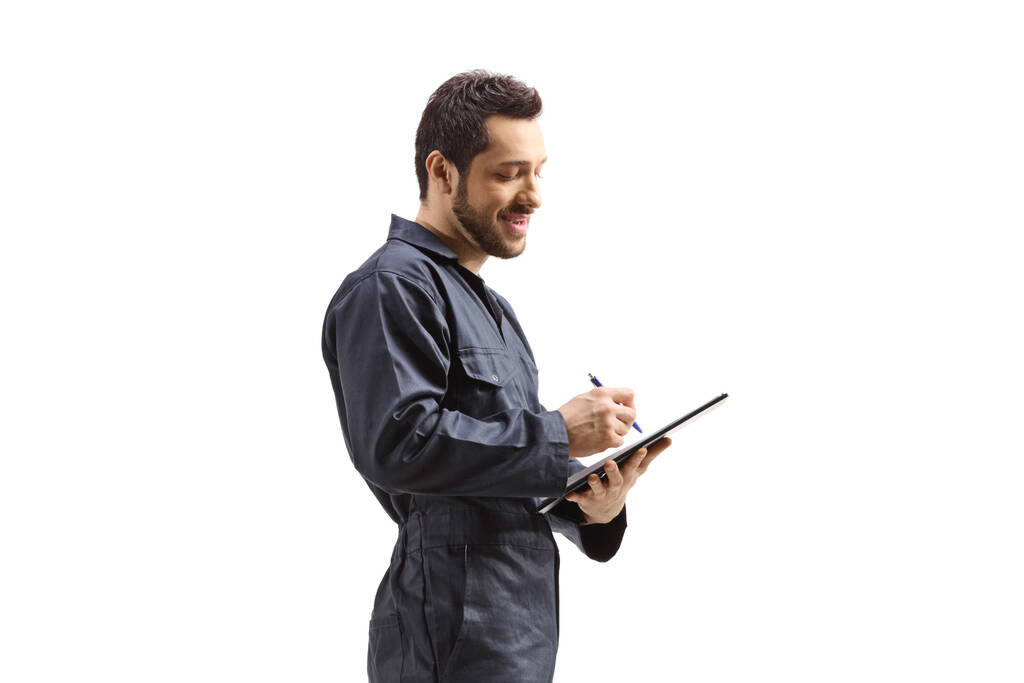 Male worker in a uniform writing on a document with a clipboard isolated on white background - Foto, immagini