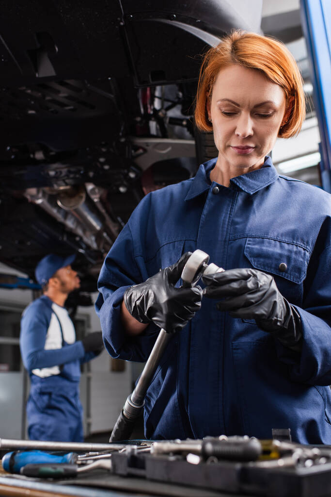 Mechanic in gloves holding wrench near blurred tools in car service  - Foto, immagini