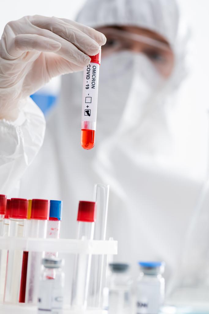un scientifique flou tenant un test d'omicron covide-19 positif pendant qu'il travaillait en laboratoire - Photo, image