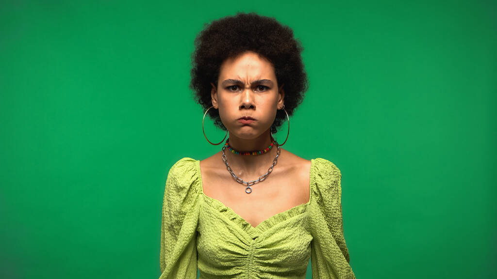 сердита молода афроамериканка набиває щоки ізольовані на зеленому
  - Фото, зображення