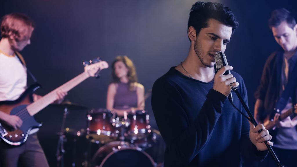 young singer performing song with blurred music band - Foto, Bild