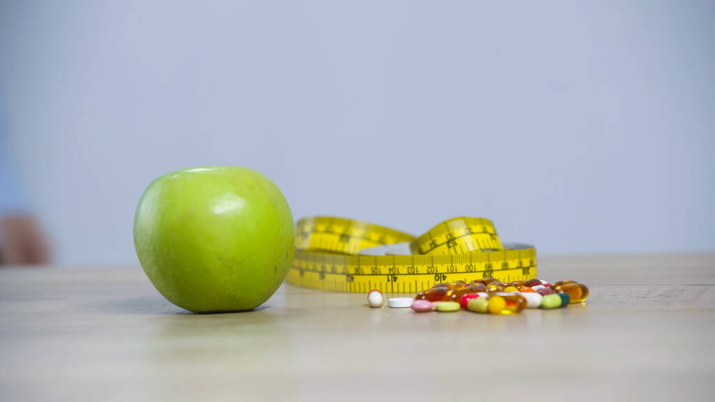 ruban à mesurer, pomme verte et vitamines isolées sur gris - Photo, image
