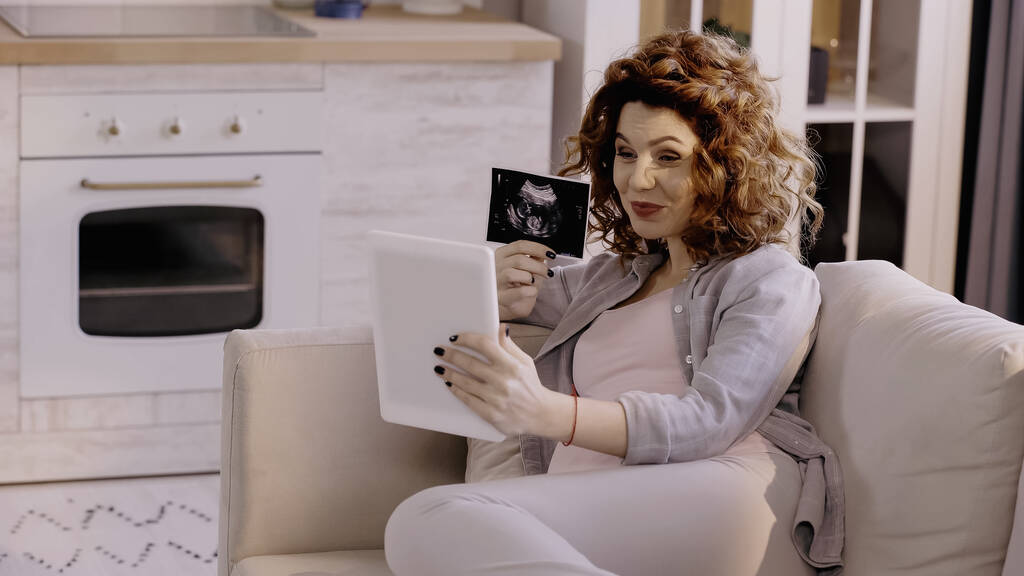 Raskaana oleva nainen näyttää vauvan ultraäänitutkimuksen digitaalisen tabletin videopuhelun aikana  - Valokuva, kuva