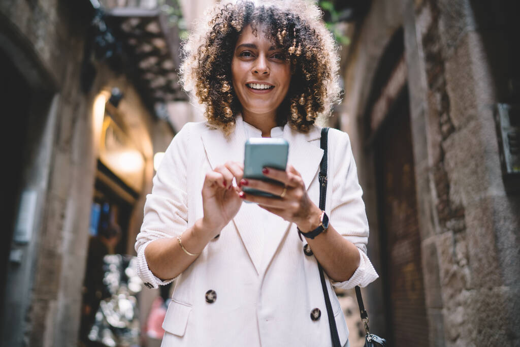 Half length portrait of pretty female blogger with digital mobile technology posing at street urbanity enjoying solo travel vacations, happy Caucasian tourism with cellular device smiling at camera - Фото, изображение