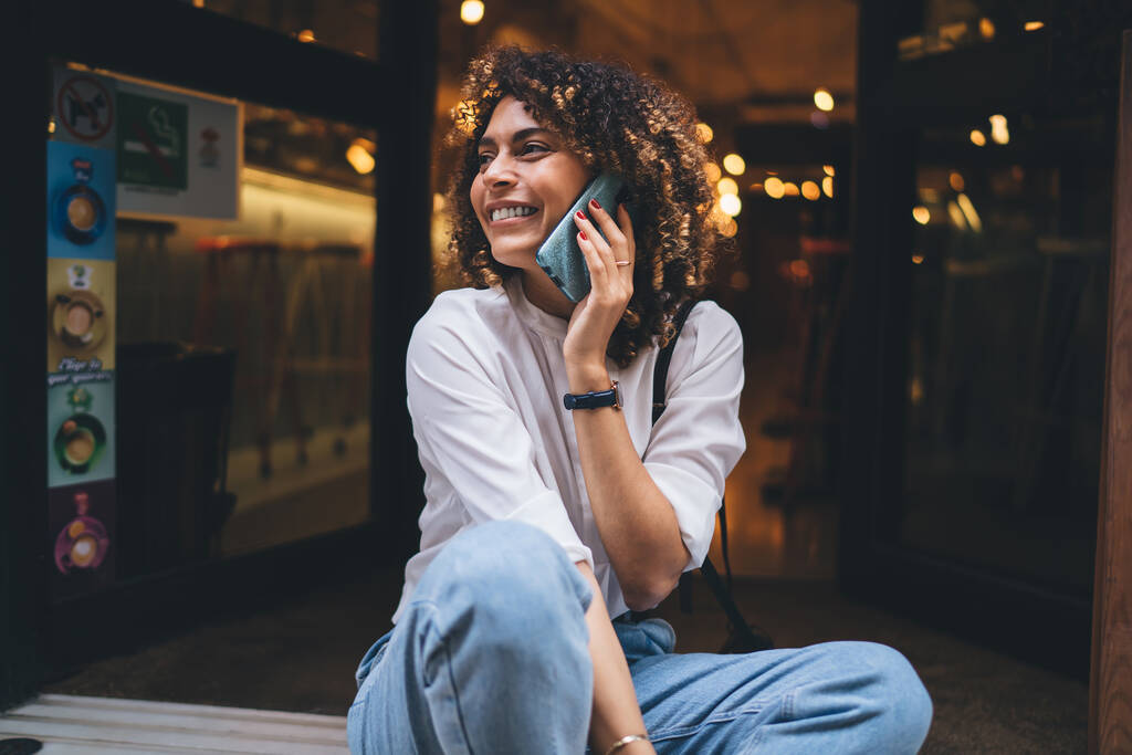 Fröhliche Touristinnen, die lächeln und lachen, während sie sich mit dem roamenden Internet verbinden, um internationale Mobilgespräche in der Stadt zu führen, glückliche kaukasische Millennials, die Handy-Kommunikation genießen - Foto, Bild
