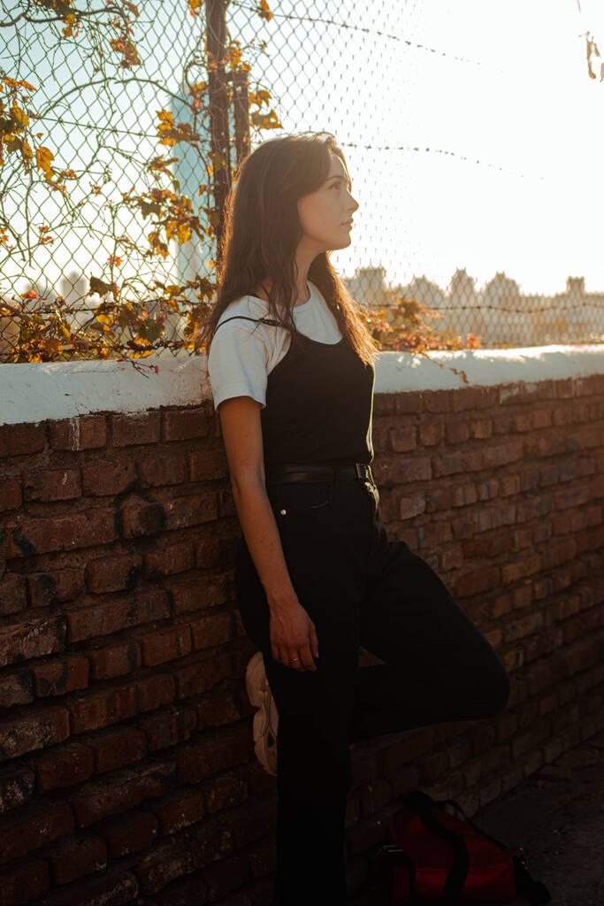 fiatal gyönyörű nő fekete ruhában a város hátterében - Fotó, kép