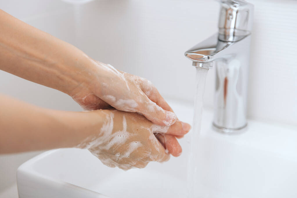 流れる水の下で手を洗う。衛生コンセプトの手の詳細。手を洗うには、コロナウイルスの予防、コロナウイルスの拡散を停止する衛生、または公共の洗面所の石鹸でこすり - 写真・画像
