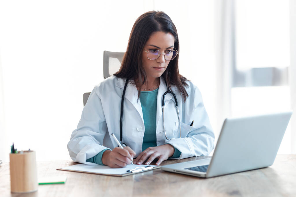 Знімок привабливого лікаря-жінки, що працює зі своїм комп'ютером в медичній консультації
. - Фото, зображення