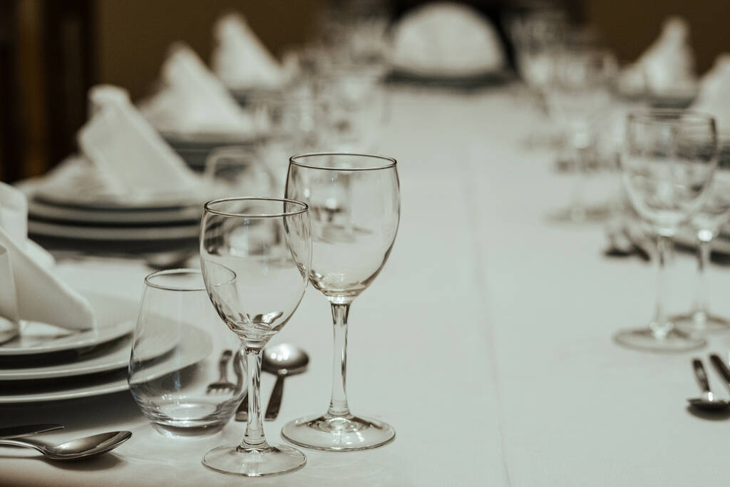 A closeup shot of a table setup with fancy dishware, glass cups, and napkins - Photo, Image