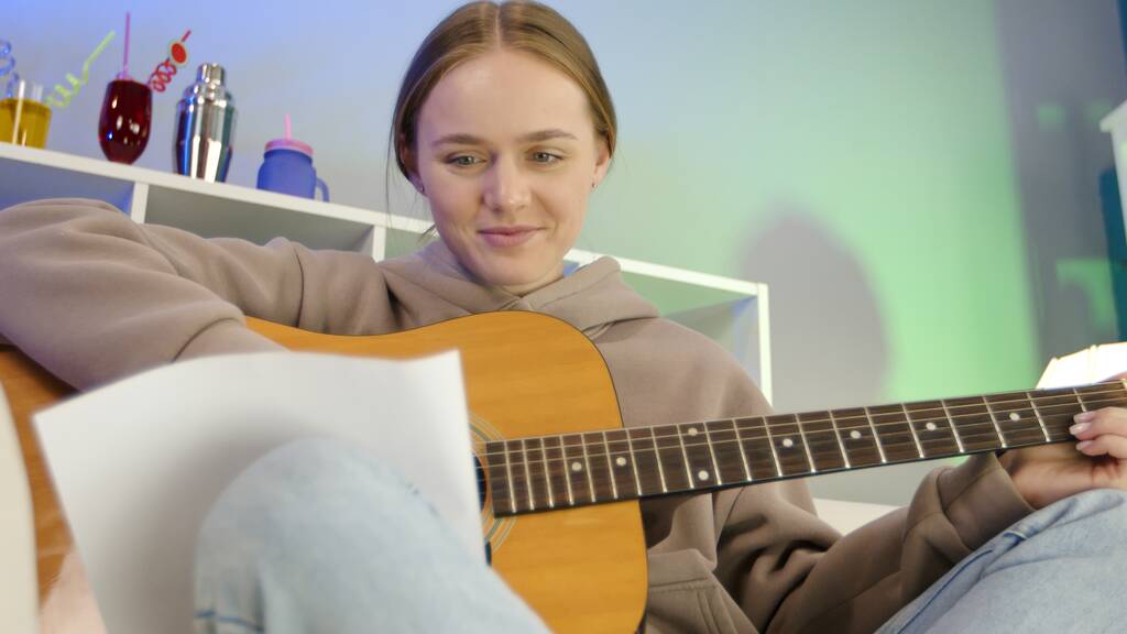 Álmodozó lány akusztikus gitározik otthon. - Fotó, kép